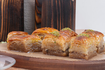Traditional turkish dessert antep baklava with pistachio on rustic table, holiday desserts concept, Delicious rhombus shaped Turkish village baklava with walnuts in a tray, Pistachio baklava closeup.