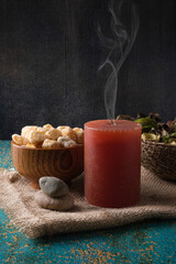 Spa session, aromatic stones, extinguished red candle and decorative flowers in a wicker basket