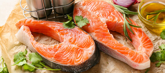 Raw salmon steaks, herbs and oil on table