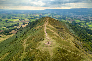 Aerial view of the summit of a small mountain surrounded by farmland (Skirrid Fawr) - obrazy, fototapety, plakaty