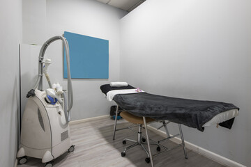 Aesthetic medicine treatment cabin with a table with a blanket, mobile electric devices with wheels to apply treatments and creams, towels and mirrors
