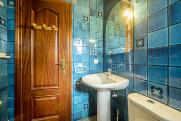 Bathroom with mirror hanging on the wall with glass shelf and super vintage blue tiles