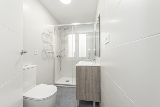 Small bathroom with a square white porcelain sink on a wooden cabinet, a frameless mirror on the wall, and a glass-enclosed shower stall