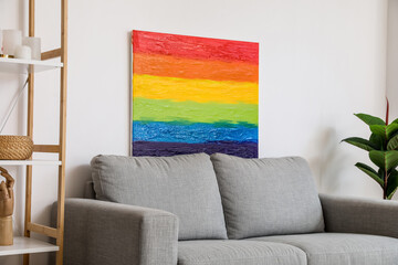 Painting of LGBT flag on sofa near light wall