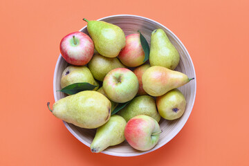 Bowl of fresh pears and apples on color background