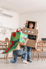 Fototapeta na wymiar Little children in cardboard costumes playing in kitchen