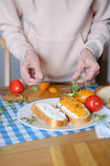 Age woman preparing healthy sandwiches with microgreens and vegetables