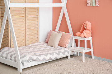 Fototapeta na wymiar Comfortable children's bed with toy near pink wall