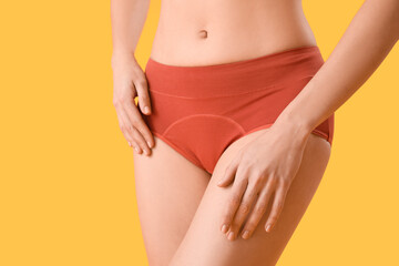 Young woman in menstrual panties on yellow background, closeup