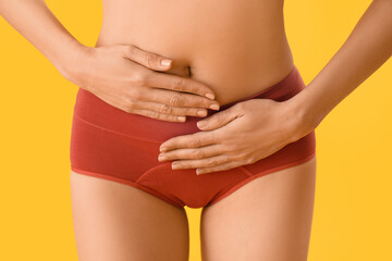 Fototapeta na wymiar Young woman in menstrual panties on yellow background, closeup