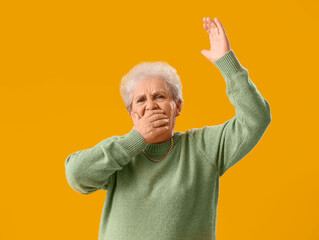 Happy senior woman in green sweater on yellow background