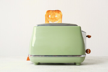 Funny slice of bread in modern toaster on white table