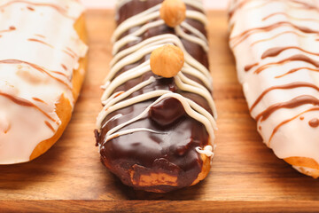 Delicious eclairs on wooden board, closeup