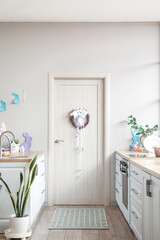 Light wooden door with Easter wreath in interior of kitchen