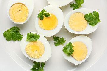 Halves of delicious boiled eggs with parsley on plate, closeup