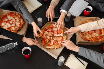 Group of business people taking tasty pizza from table in office, top view