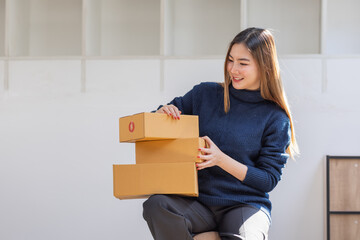 Startup small business entrepreneur of freelance Asian woman using a phone with box Cheerful success Asian woman her hand lifts up online marketing packaging box and delivery SME idea concept