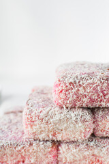 Pink lamingtons on a ceramic plate Australian raspberry lamingtons, small cakes covered in desiccated coconuts