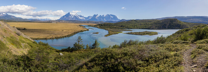 Serrano River, golden pampas and snowy mountains of Torres del Paine National Park in Chile,...