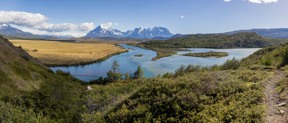 Serrano River, golden pampas and snowy mountains of Torres del Paine National Park in Chile,...