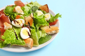 Plate of delicious salad with boiled eggs and jamon on blue background