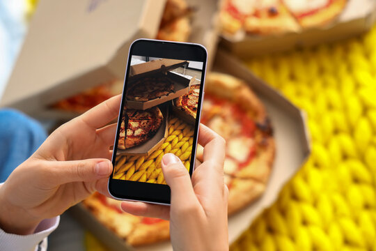Young woman with mobile phone taking picture of tasty pizza in bedroom, closeup