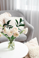 Vase with ranunculus flowers on table in living room, closeup