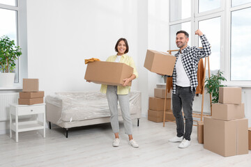 Happy couple with moving boxes in new apartment