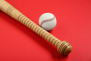 Wooden baseball bat and ball on red background. Sports equipment