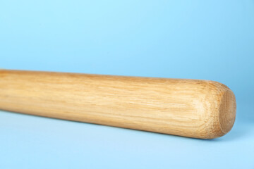 Wooden baseball bat on light blue background, closeup. Sports equipment