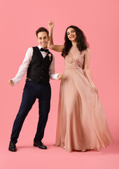 Beautiful couple dressed for prom dancing on pink background © Pixel-Shot
