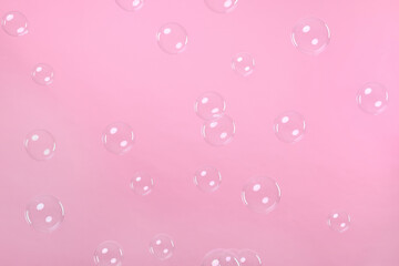 Many beautiful soap bubbles on pink background