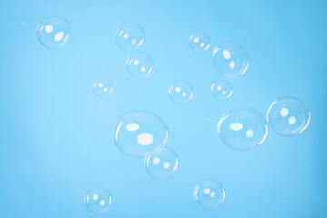 Many beautiful soap bubbles on light blue background
