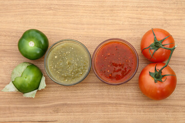 Tasty salsa sauces and different tomatoes on wooden table, flat lay