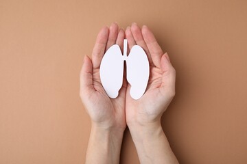 Quitting smoking concept. Woman holding paper lungs on beige background, top view