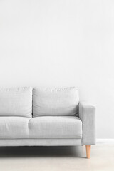 Stylish grey sofa near white wall