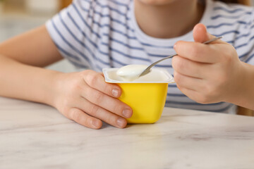 Cute little girl with tasty yogurt at white marble table, closeup