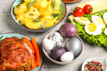 Fototapeta na wymiar Bowl with beautiful painted eggs and tasty dishes for Easter dinner on table, closeup