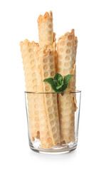 Glass with delicious wafer rolls and mint isolated on white background