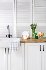 Easter eggs, bunny, tulip flowers and sink on white kitchen counter
