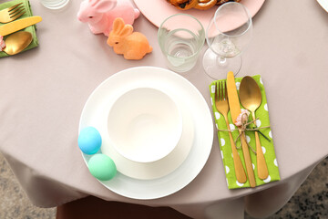 Set of plates and cutlery with Easter eggs and flower on table