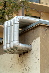 Vents bending out building onto roof of stucco white and brown facade in urban or industrial area of neighborhood city
