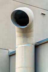 Curved pipe for venting smoke and chemicals out of industrial factory for carbon emissions and polutions in city neighborhood