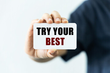 Try your best text on blank business card being held by a woman's hand with blurred background. Business concept to encourage audience to do the best as they can.