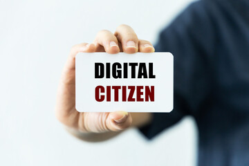 Digital citizen text on blank business card being held by a woman's hand with blurred background. Business concept about digital citizen.