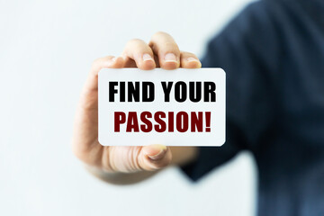 Find your passion text on blank business card being held by a woman's hand with blurred background. Business concept about finding passion.