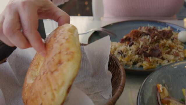 Woman eats oriental flatbread in street cafe while enjoying her meal.