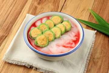 Es Pisang Ijo, Ripe Banana Rolled with Green Thin Crepes, Rice Porridge and Red Syrup.
