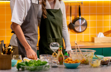 Man & Woman in the kitchen wearing apron preparing food