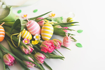 Fototapeta na wymiar Happy Easter. Stylish dyed easter eggs with spring flowers on white background. Pink tulips with colorful eggs